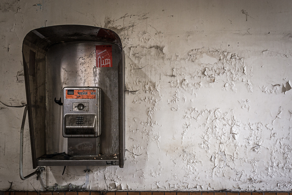 Ancienne cabine téléphonique Belgacom accrochée à un mur.