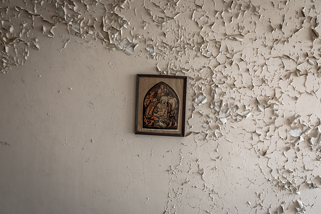 Mur à la peinture écaillée, décoré d'un cadre de travers contenant une illustration de Jésus, Marie, Joseph et les apôtres ...