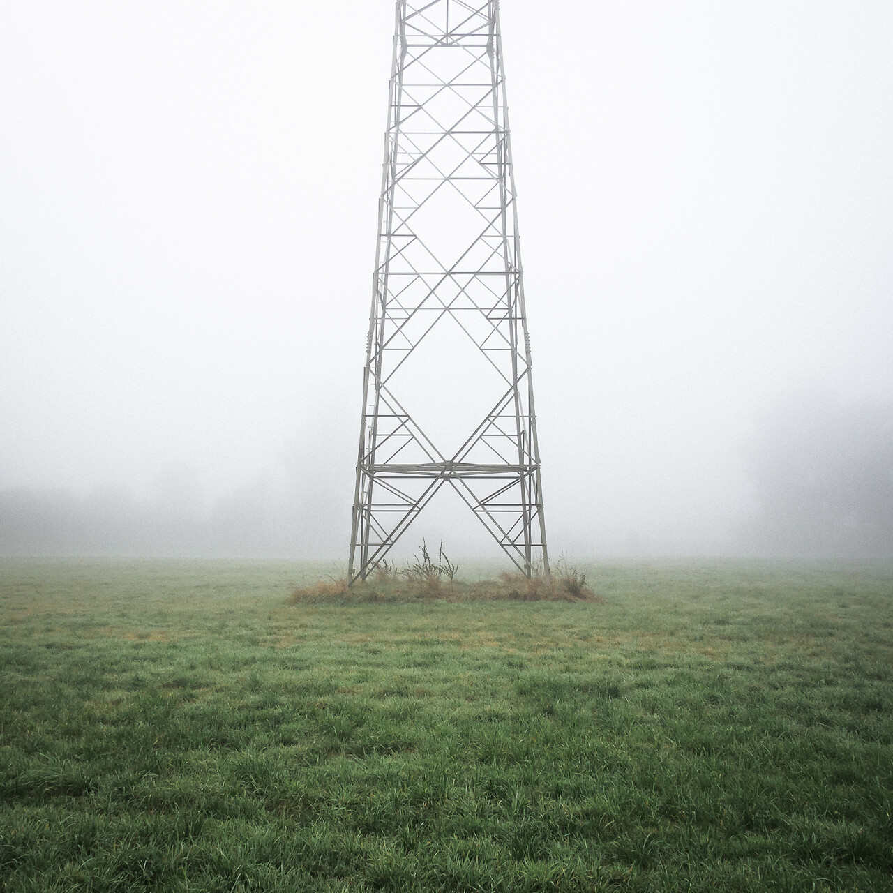 Base d’un pylône électrique dans le brouillard.