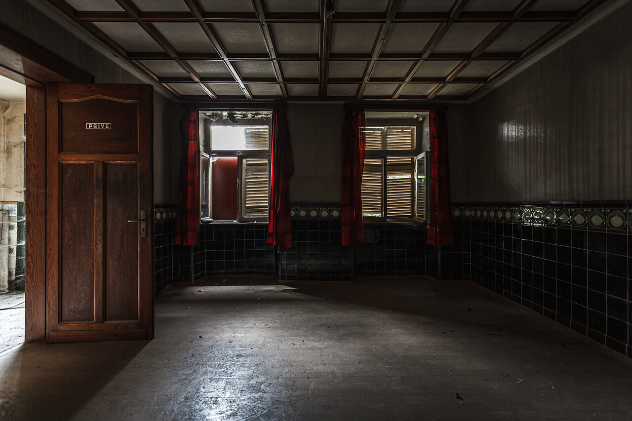 Plan large sur une pièce avec parquet donnant sur deux fenêtres occultées par des volets à lamelles...