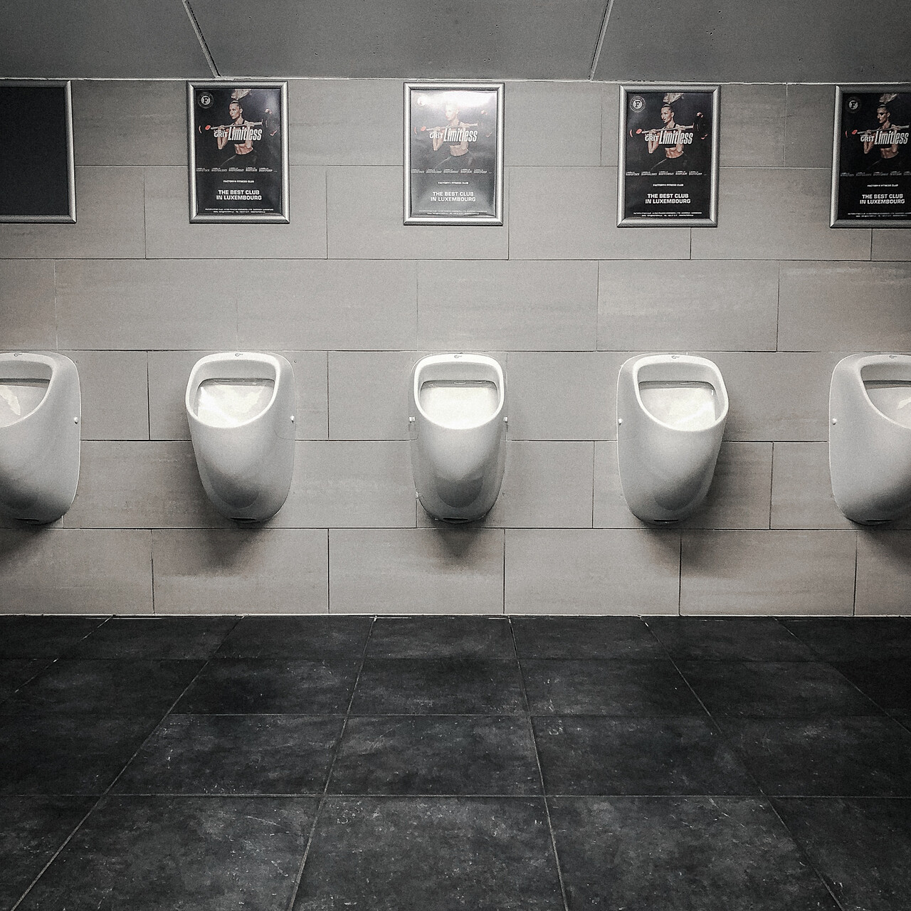 Quatre urinoirs surmontés d'affiches publicitaires