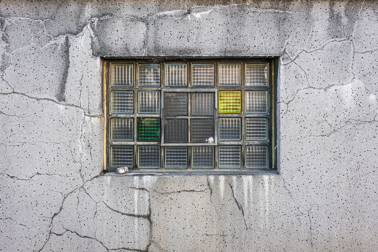 Plein cadre sur la façade fissurées et sa fenêtre en briques de verre de la brasserie Simon à Wiltz.