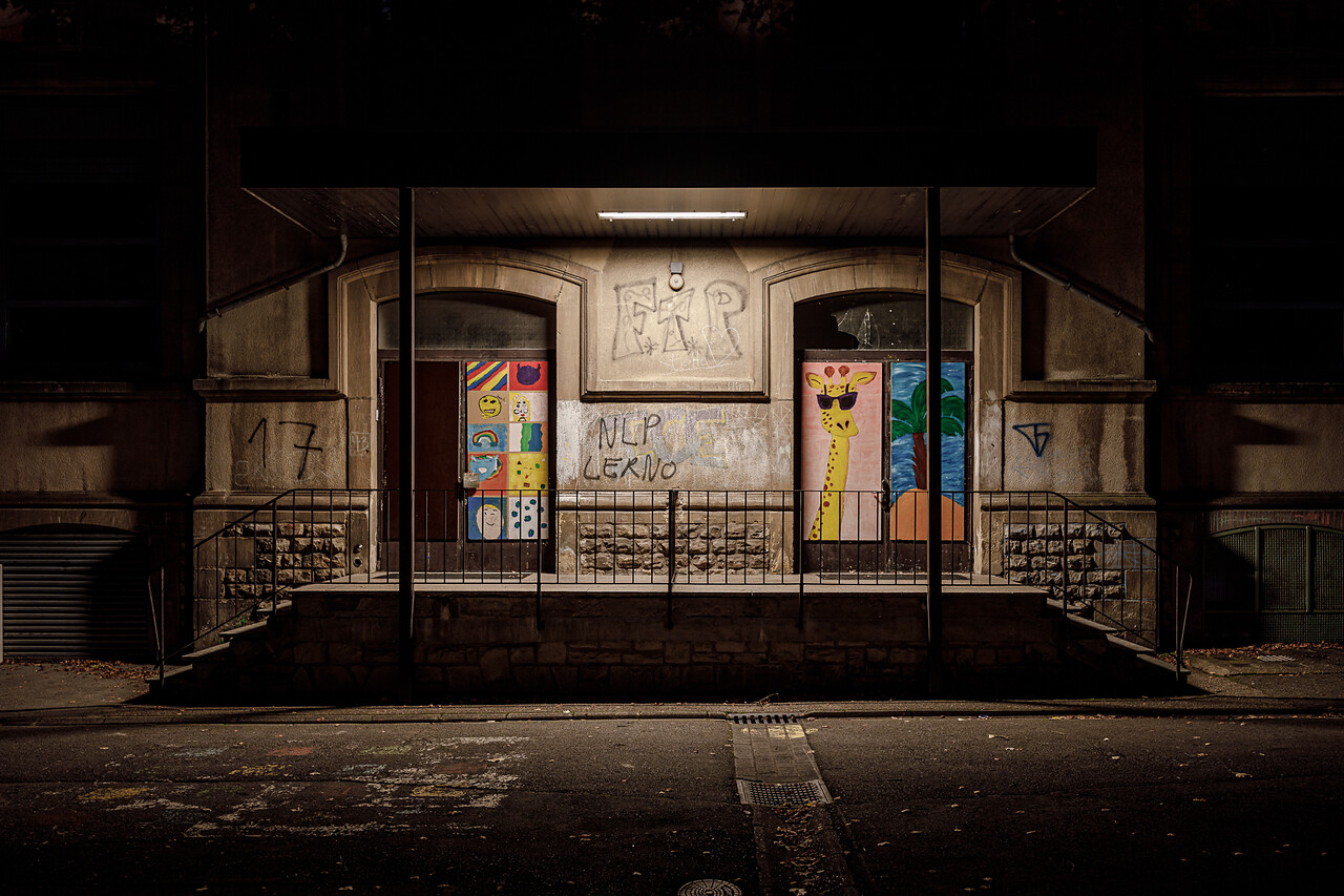 Entrée de deux portes colorées: une avec dessins (smiley, arc-en-ciel) et l'autre une girafe, graffitis (FTP, NLP LERNO) sur les murs. Photo de nuit