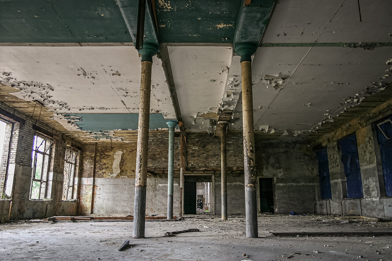 Perspective sur une grande salle délabrée et ses colonnes.
