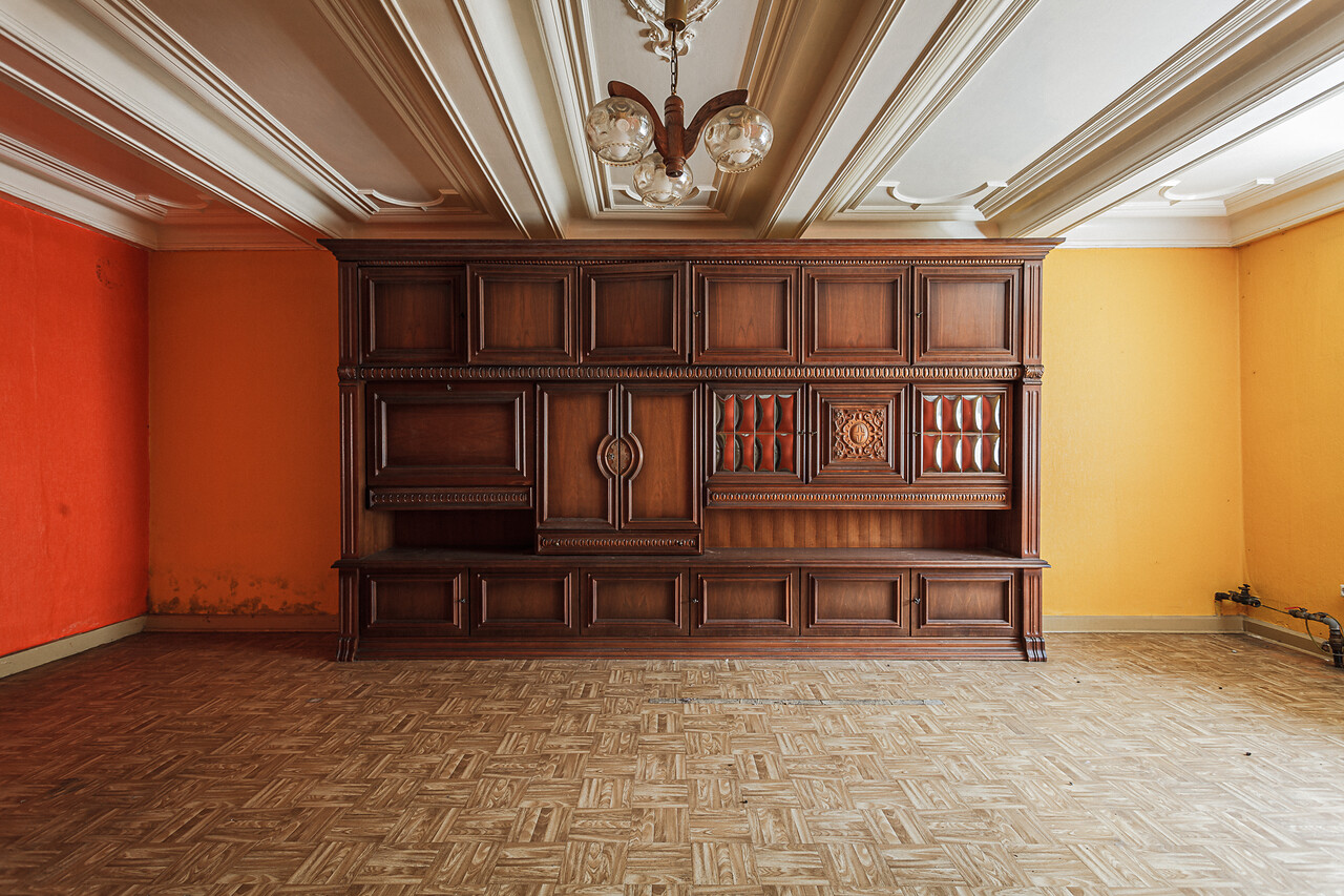 Perspective sur un salon avec parquet et contenant un vieux buffet gigantesque...