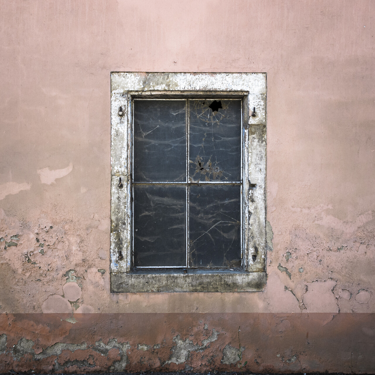 Vieille façade de ferme avec sa fenêtre aux carreaux brisés.