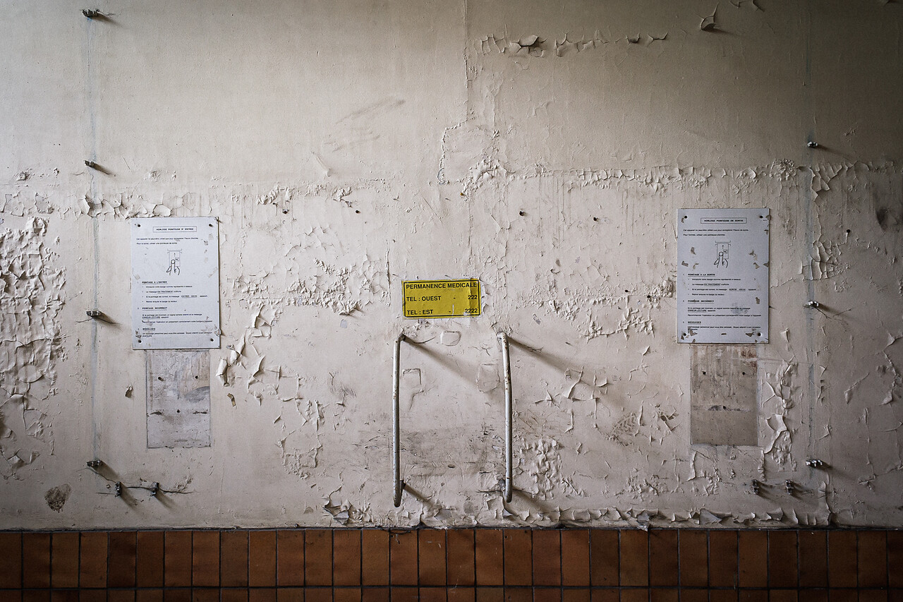 Mur décrépi avec affiches d'informations et ancien emplacement d'une pointeuse.
