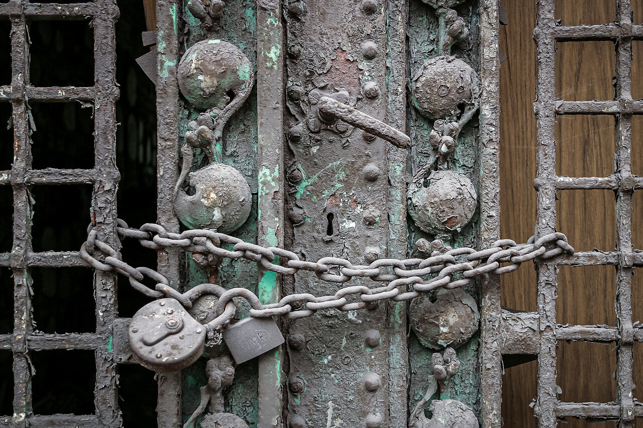 Gros plans sur une chaine et des cadenas sur une porte délabrée.
