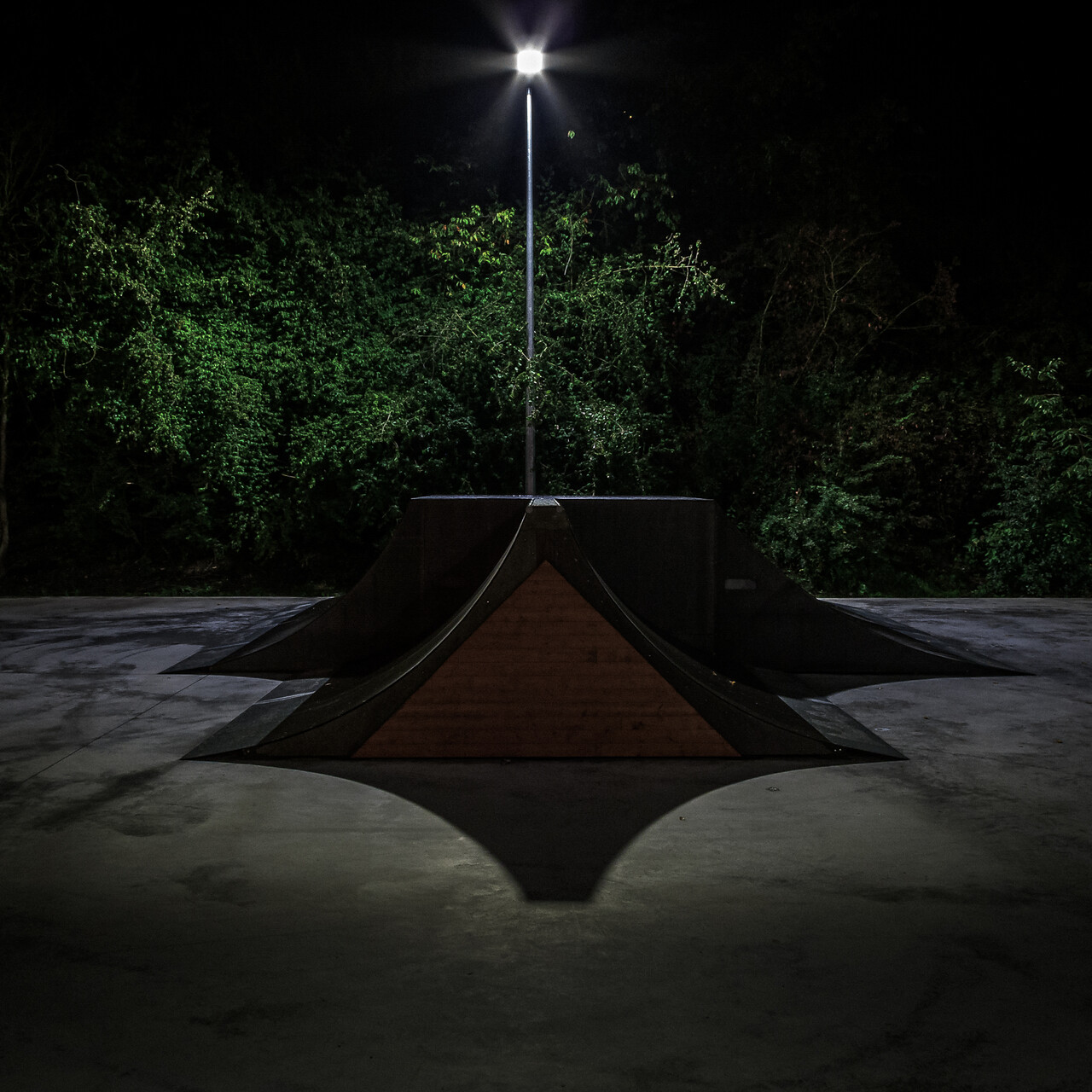 Rampe d’un skatepark éclairée la nuit.