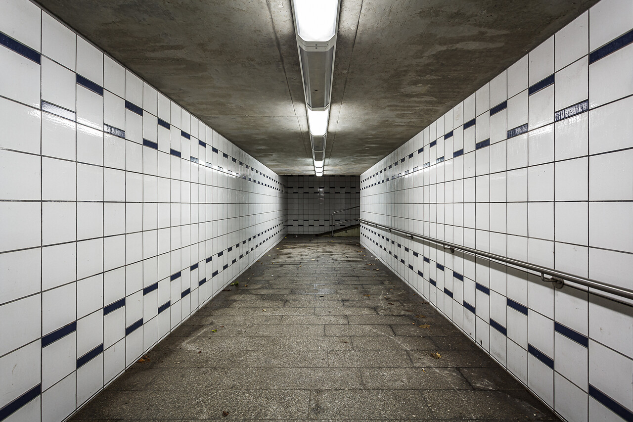 Souterrain aux voies de chemin de fer, murs carrelés et éclairé aux néons...