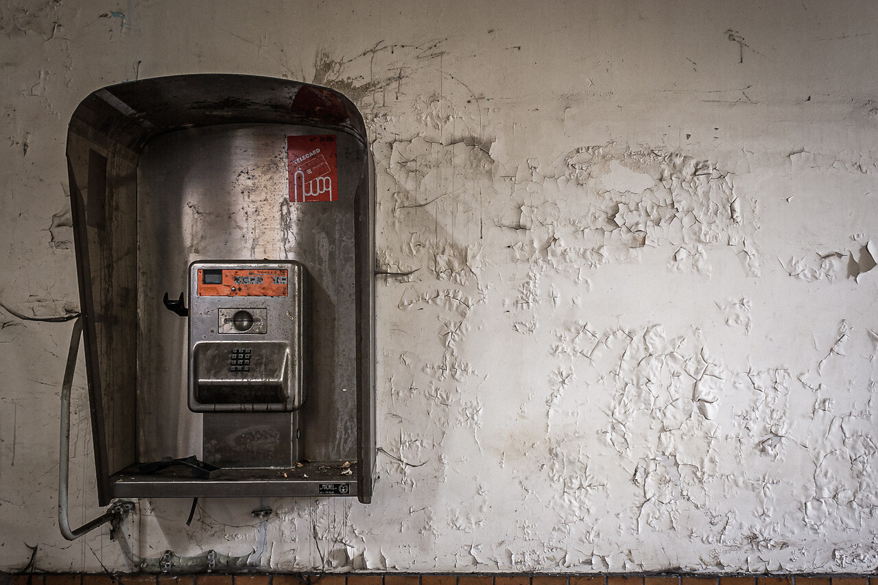 Ancienne cabine téléphonique Belgacom accrochée à un mur.