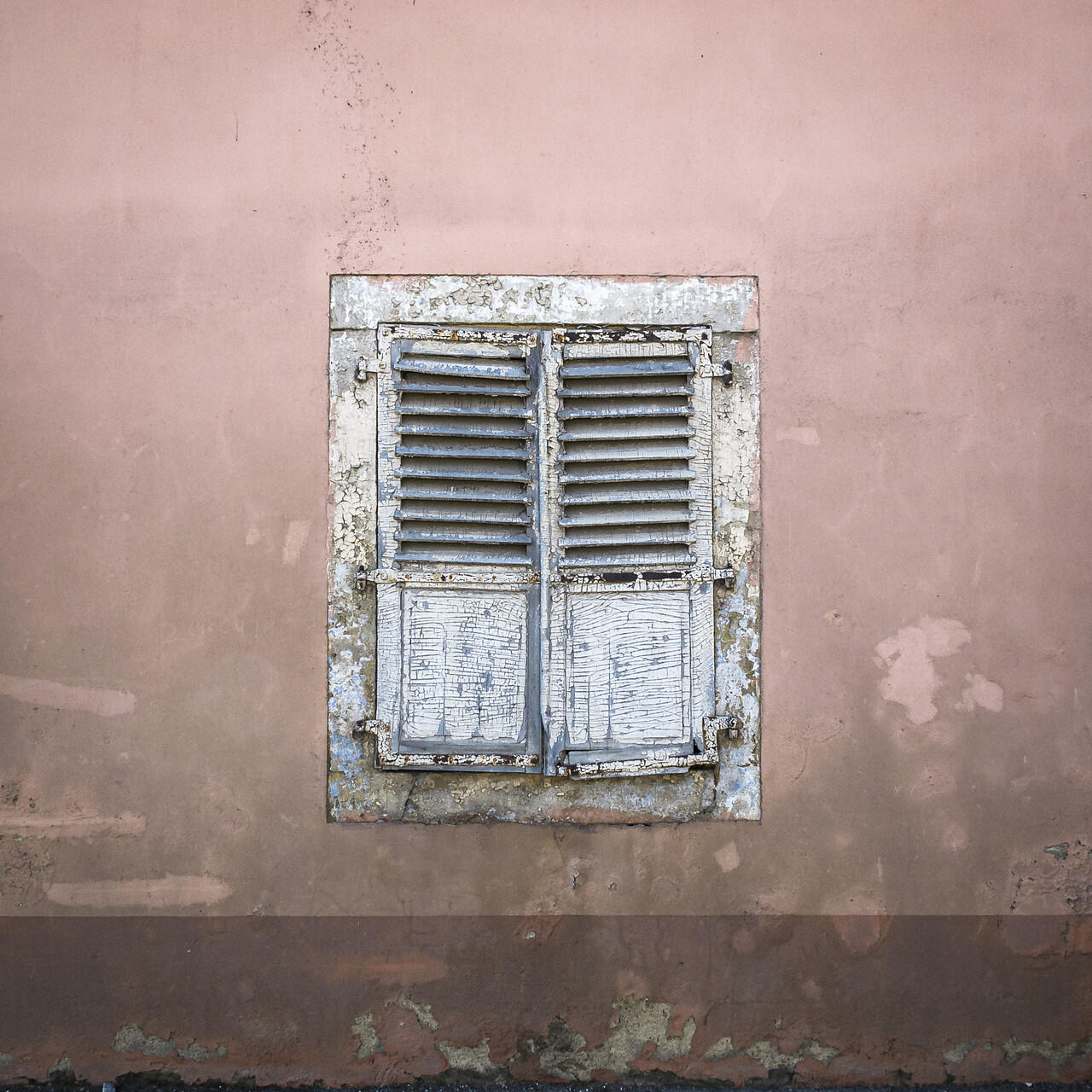 Vieille façade de ferme avec sa fenêtre occulté par des volets.