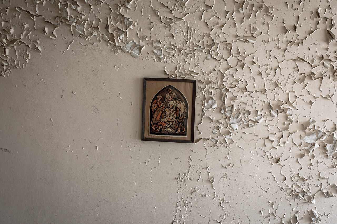 Mur à la peinture écaillée, décoré d'un cadre de travers contenant une illustration de Jésus, Marie, Joseph et les apôtres  ...