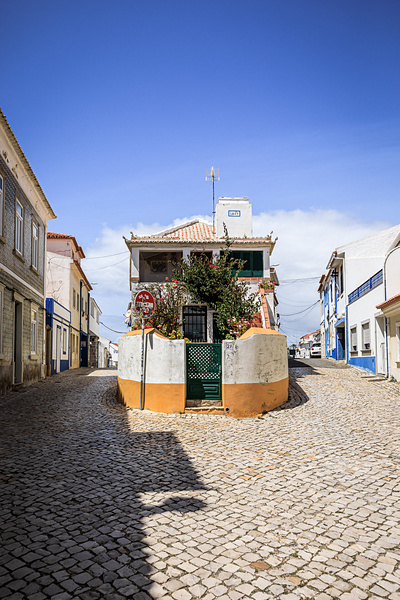 Une maison blanche datant de 1869 au 2A, à l'intersection de 2 rues pavées de Ericeira au Portugal. Un panneau de signalisation couvert d'autocollants.