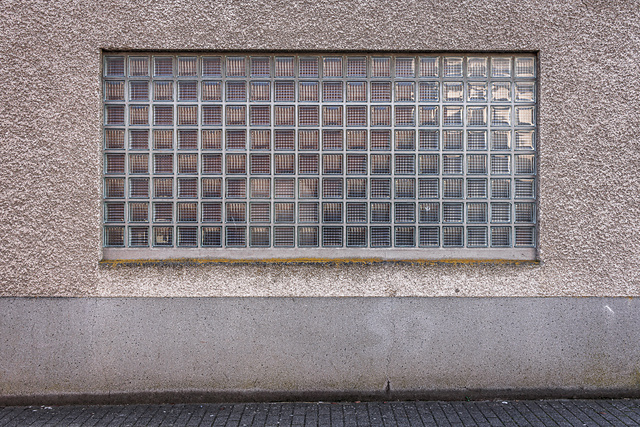 Plein cadre sur une fenêtre en briques de verre d'un bâtiment proche, probablement un bureau, de la brasserie Simon à Wiltz.