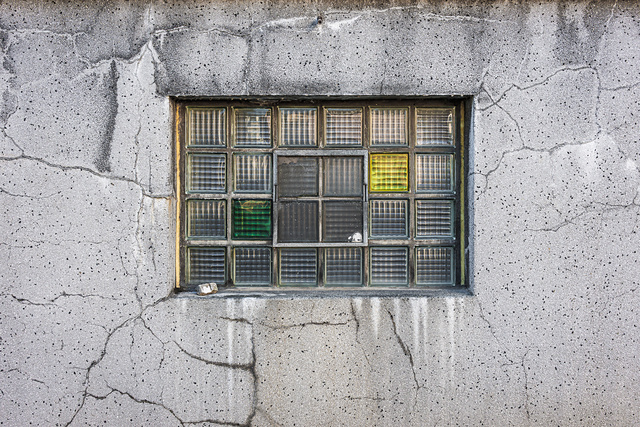 Plein cadre sur la façade fissurées et sa fenêtre en briques de verre de la brasserie Simon à Wiltz.