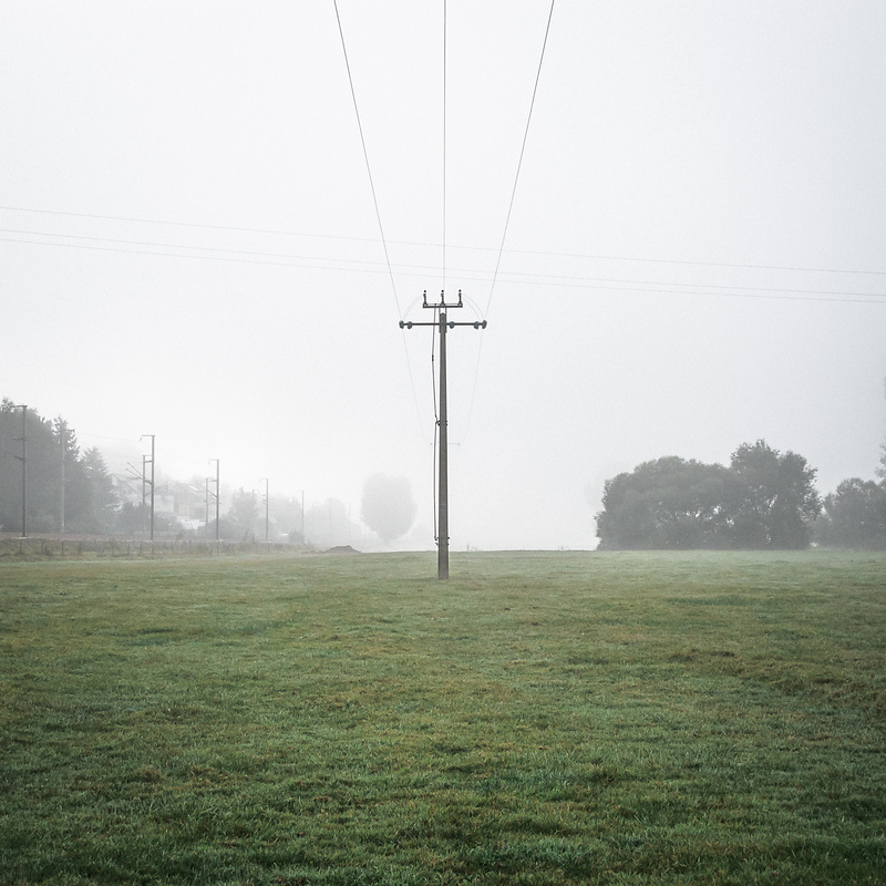 Poteau électrique au milieu d’un champ dans le brouillard.