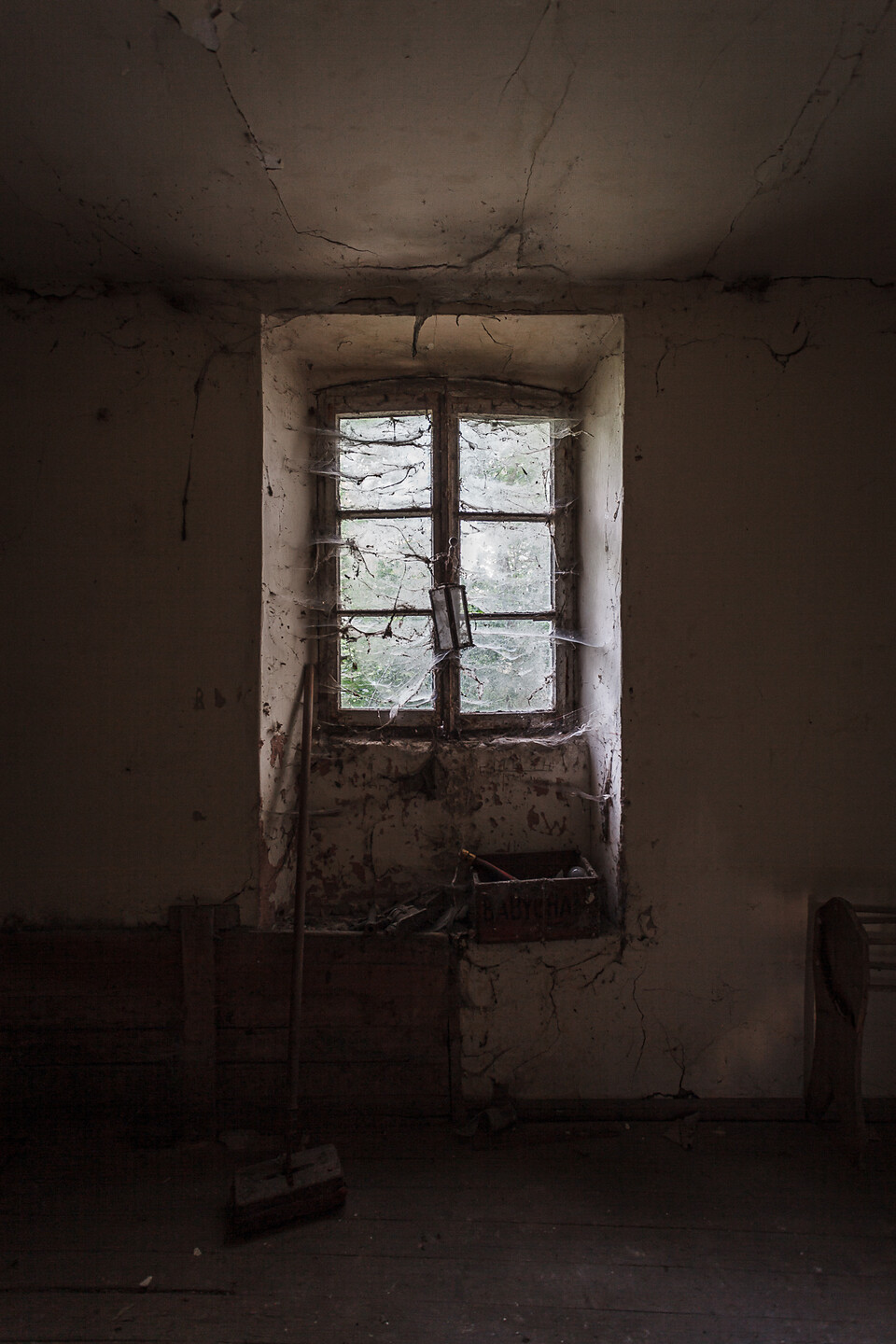 Vue intérieure sur une fenêtre à battants et croisillions couverte de toiles d'araignées...