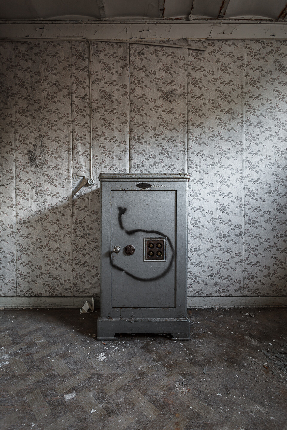 Coffre fort taggé contre un mur couvert décoré de papier peint à motifs...