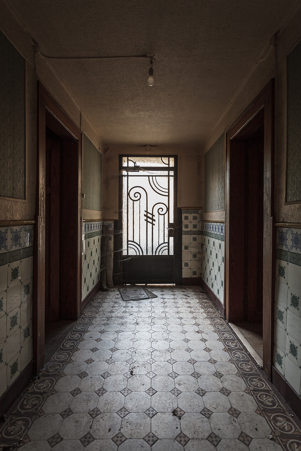 Perspective sur un corridor d'entrée à carrelages à motifs au sol et au murs...