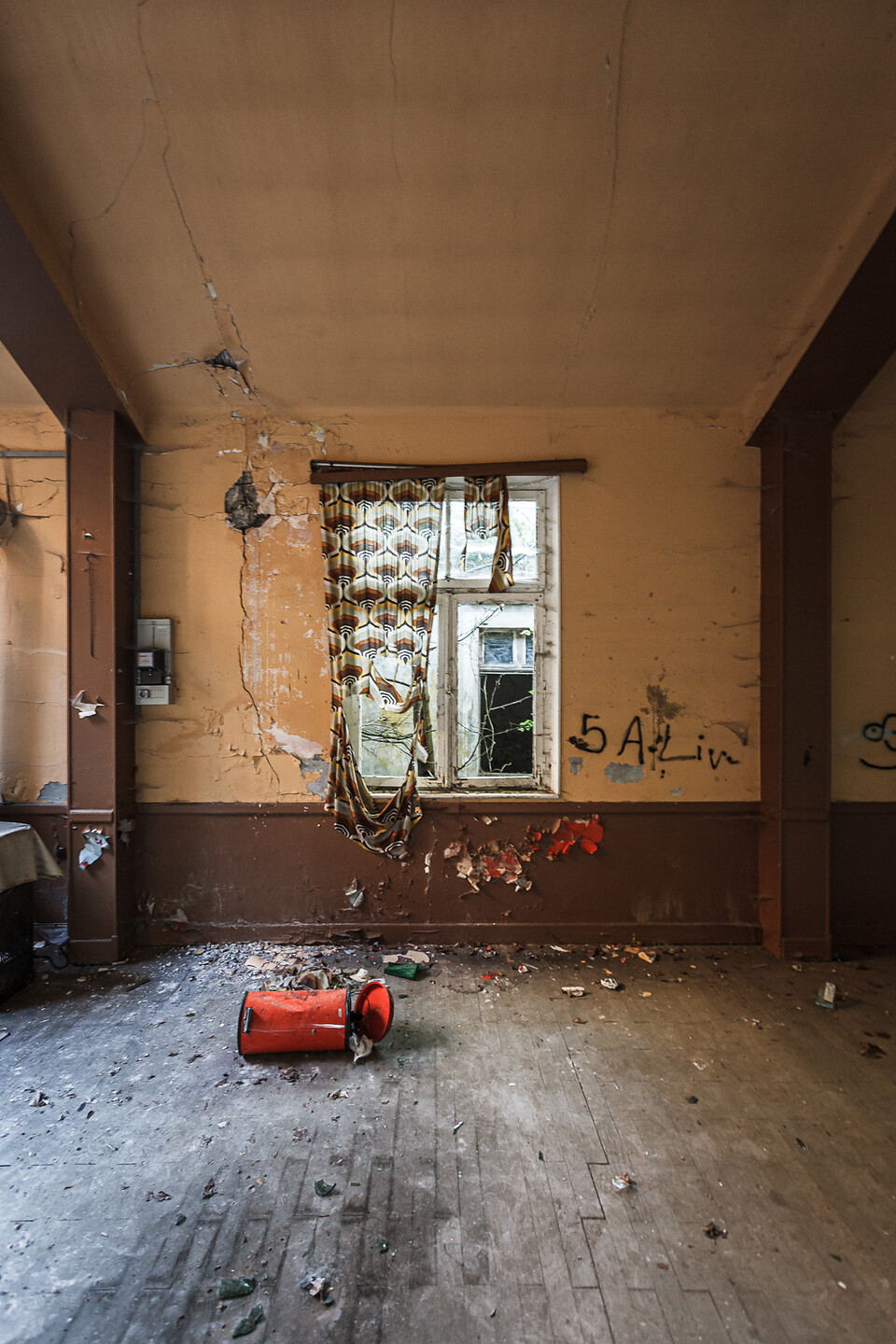 Plan large d'une vue intéreieurs sur une fenêtre décorée de rideaux à motifs et déchirés...