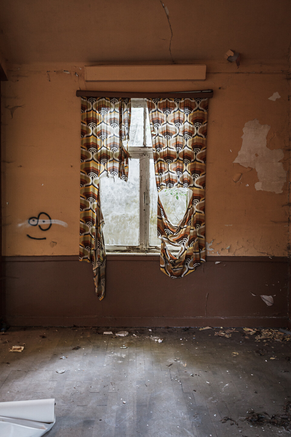 Vue intéreieurs sur une fenêtre décorée de rideaux à motifs et déchirés...