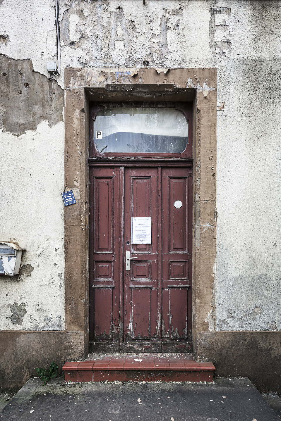 Façade décrépie et porte d'entrée d'un café à l'abandon.