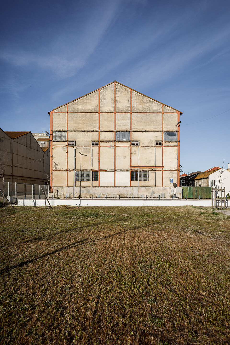 Bâtiment industriel (Companhia União Fabril) en béton avec des structures métalliques rouges, des fenêtres grillagées et sous un ciel bleu.