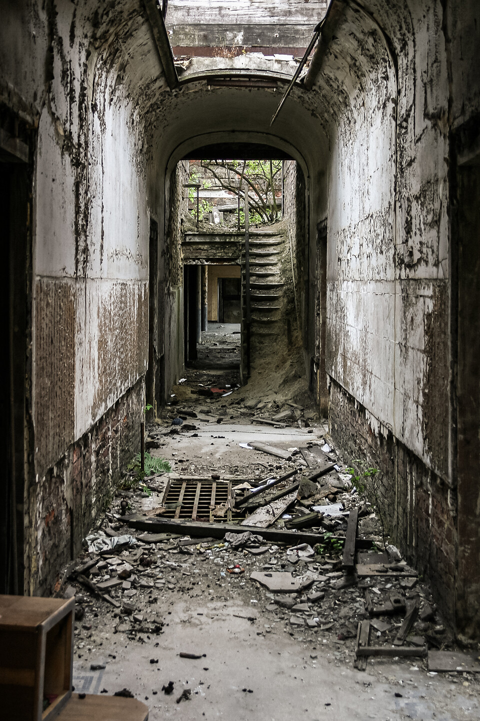 Perspective sur un couloir délabrée et encombré.