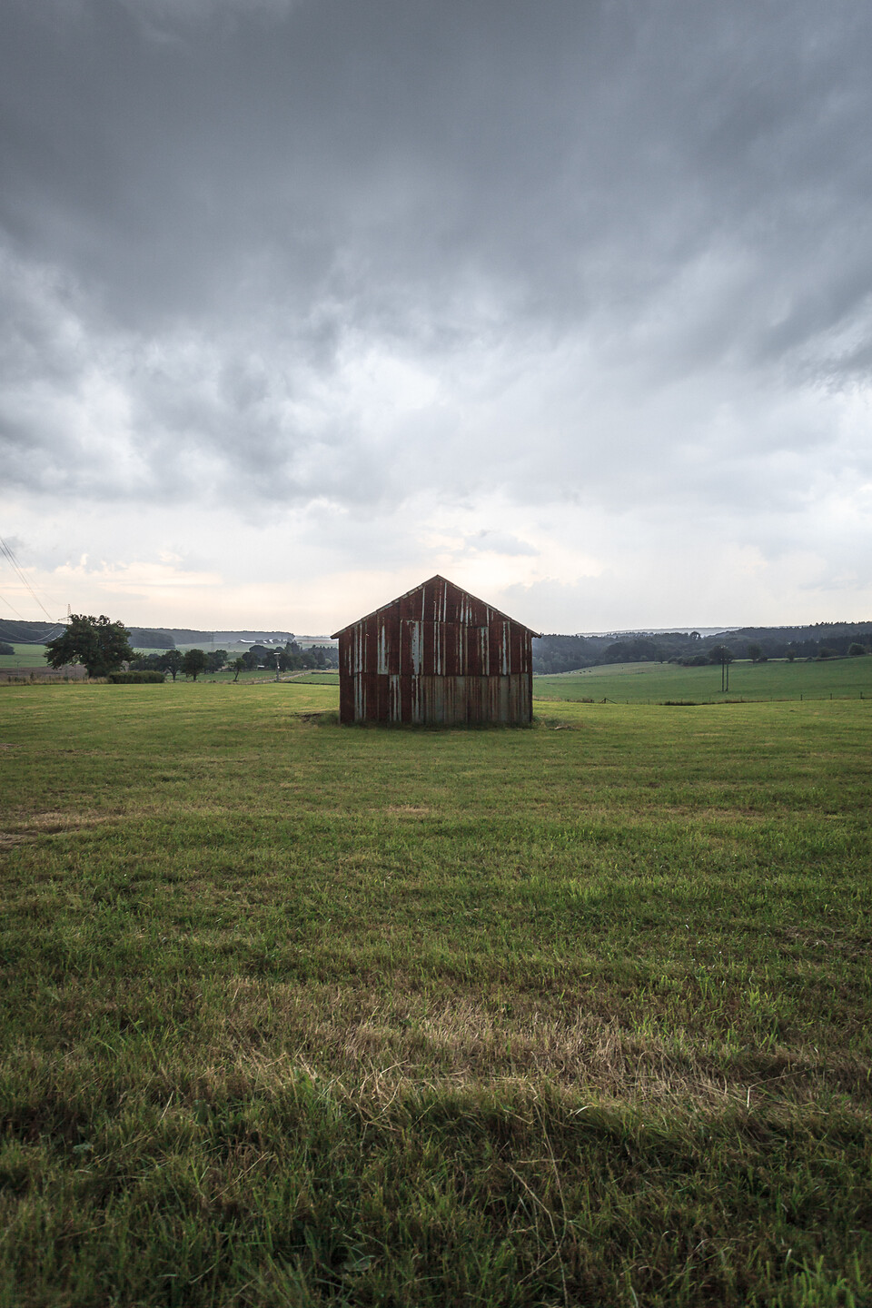 Un ciel menaçant au dessus d'une grange en tôles rouillées au beau milieu d'un champs