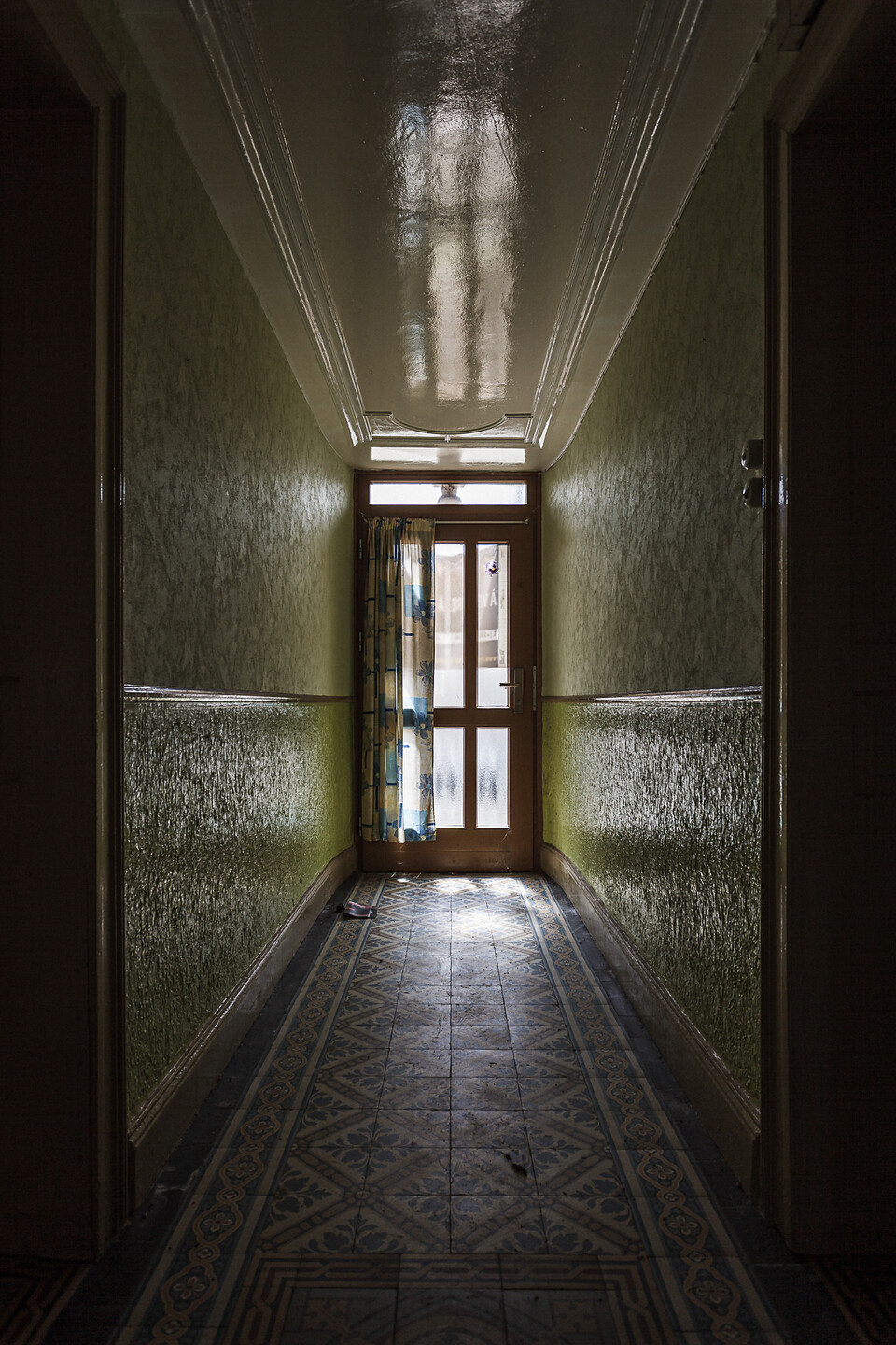 Perspective sur un corridor d'entrée à carrelages à motifs et aux murs verts...