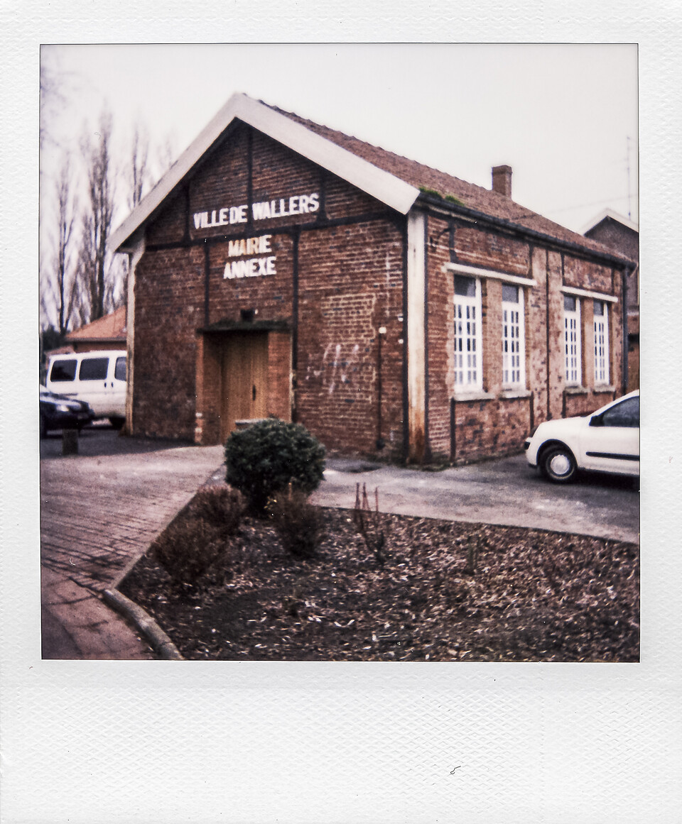 Polaroid d'un bâtiment en briques rouges à Wallers, utilisé comme mairie annexe, avec l'inscription 'Ville de Wallers' en façade.