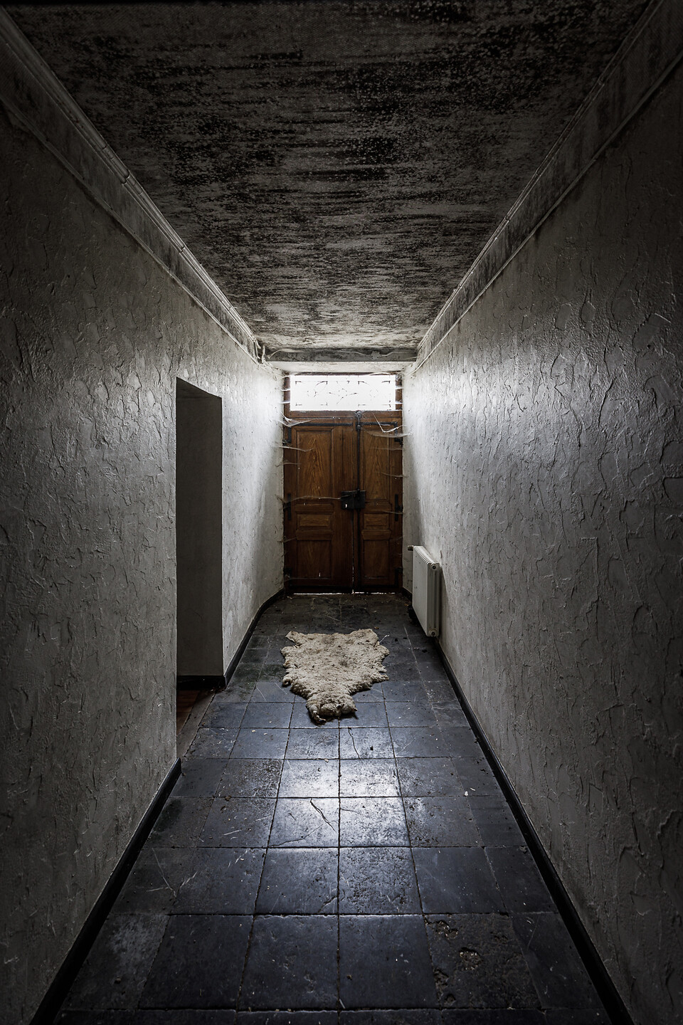 Hall d'entrée, ses murs en crépi, son sol en pierres blues et sa peau de mouton en guise de paillasson...