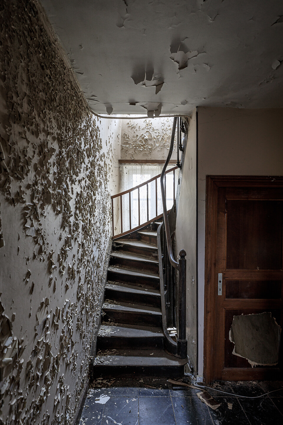 Cage d'escalier apposée sur un mur écaillé et l'escalier affaissé par le poids des années ...