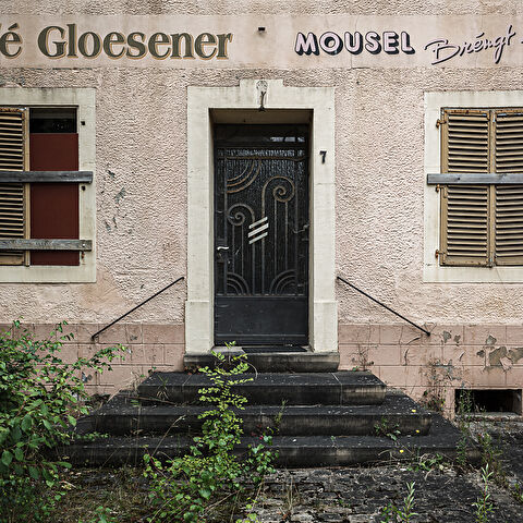 Façade délabrée, porte et volets à lamelles d'un café...