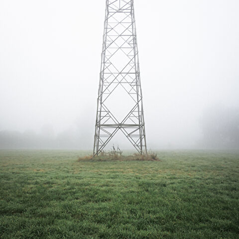 Base d’un pylône électrique dans le brouillard.