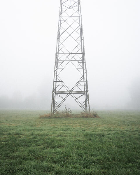Base d’un pylône électrique dans le brouillard.