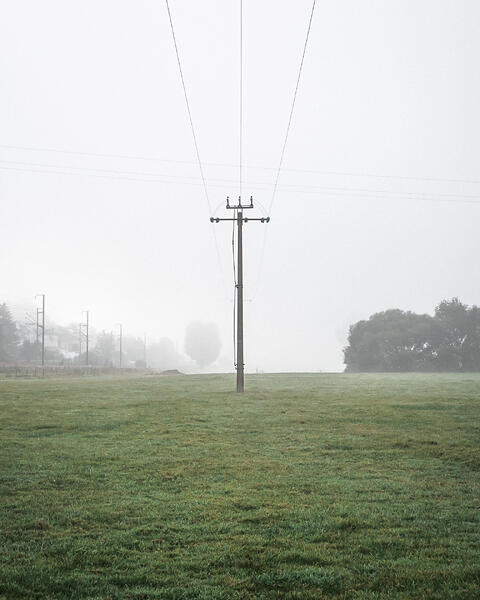 Poteau électrique au milieu d’un champ dans le brouillard.