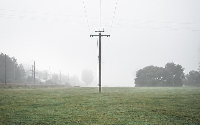 Poteau électrique au milieu d'un champ dans le brouillard.