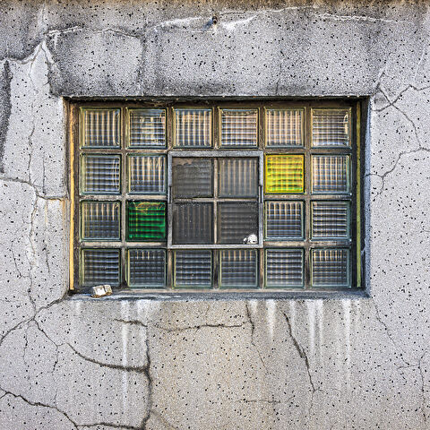 Plein cadre sur la façade fissurées et sa fenêtre en briques de verre de la brasserie Simon à Wiltz.