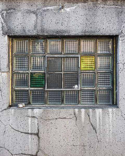 Plein cadre sur la façade fissurées et sa fenêtre en briques de verre de la brasserie Simon à Wiltz.