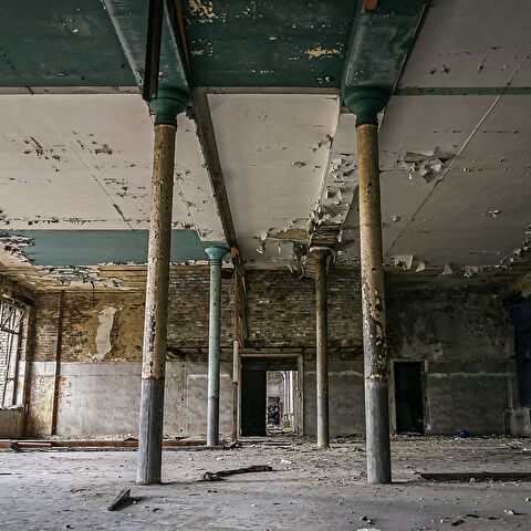 Perspective sur une grande salle délabrée et ses colonnes.