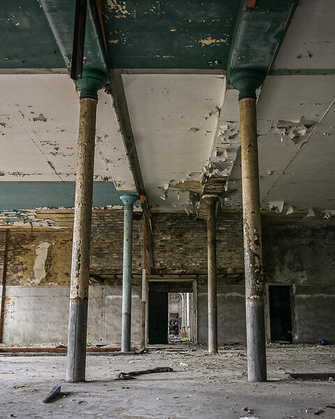 Perspective sur une grande salle délabrée et ses colonnes.