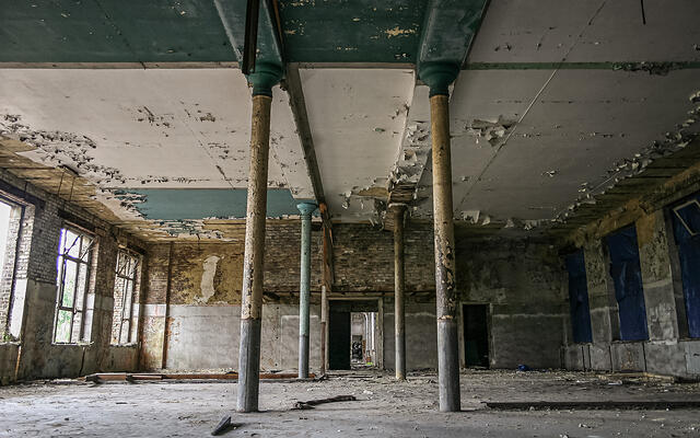 Perspective sur une grande salle délabrée et ses colonnes.