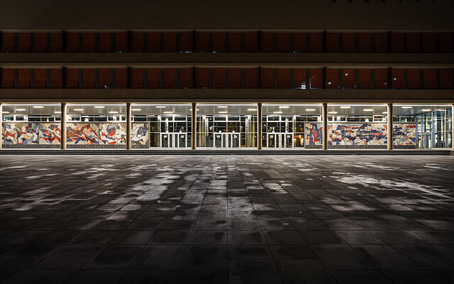 Vue nocturne de face du parvis de l'Athénée de Luxembourg à Hollerich, mettant en valeur les lignes géométriques et l'architecture épurée sous un éclairage de nuit.