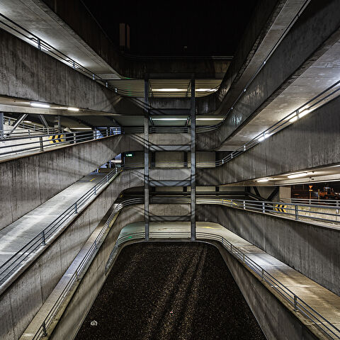 Perpective sur les rampes de parking éclairée la nuit.