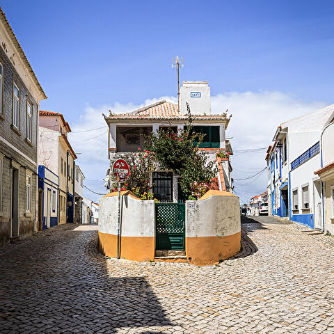 Une maison blanche datant de 1869 au 2A, à l'intersection de 2 rues pavées de Ericeira au Portugal. Un panneau de signalisation couvert d'autocollants.