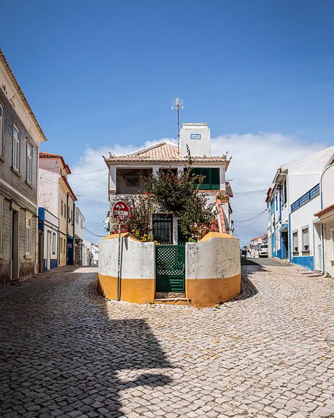 Une maison blanche datant de 1869 au 2A, à l'intersection de 2 rues pavées de Ericeira au Portugal. Un panneau de signalisation couvert d'autocollants.