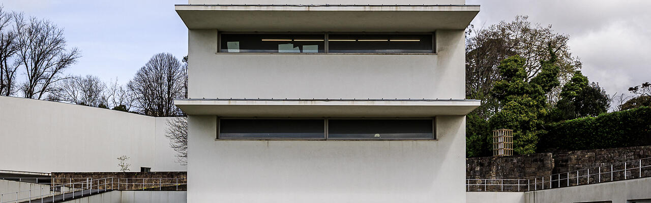 Façade côté rue de la 'Torre H' aux ouvertures géométriques et fenêtres en longueur, s'élevant derrière une pelouse verte. (Massarelos, Porto, Portugal)