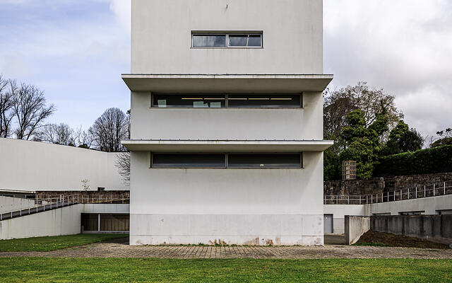 Façade côté rue de la 'Torre H' aux ouvertures géométriques et fenêtres en longueur, s'élevant derrière une pelouse verte. (Massarelos, Porto, Portugal)